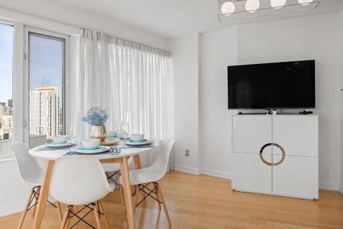 a white dining room with a table and a tv at Stunning 27th Floor Suite - Close to Eaton Centre -The Roland in Toronto