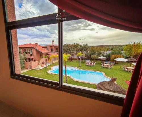 a window view of a swimming pool and a yard at Tynass Ferme - Atlas Room Fes in Douar er Rouazi