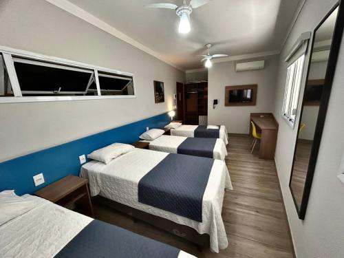 una camera d'albergo con quattro letti e una finestra di Vinds Economic Hotel a Ipatinga