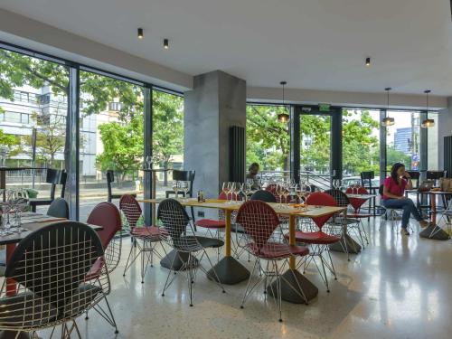 a restaurant with tables and chairs and windows at ibis Styles Bucharest Erbas in Bucharest