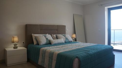 a bedroom with a large bed with a blue blanket at casa2sonhos in Água de Pena