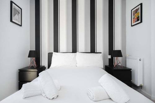 a bedroom with a white bed with black and white stripes at Stunning 2BR flat with balcony in Maidenhead