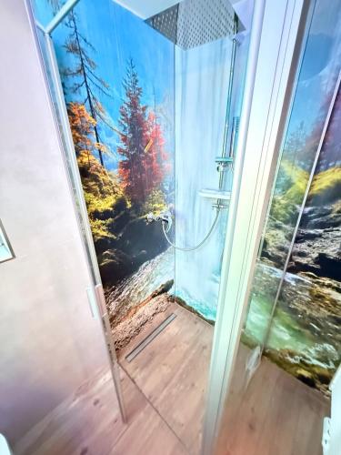a shower door with a painting of a forest at Chalet im Wald mit Sauna in Schönwalde