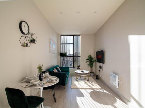 a living room with a table and a couch and a clock at Modern 1 bed Apartment in Central Leeds in Central Station