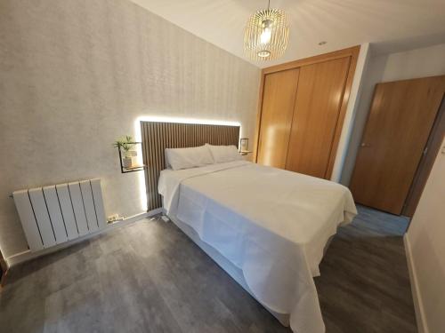 a bedroom with a white bed and a wooden door at Doña Urraca in Porriño
