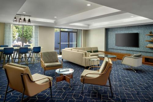 a living room with a couch and chairs and a television at Courtyard by Marriott Frederick in Frederick