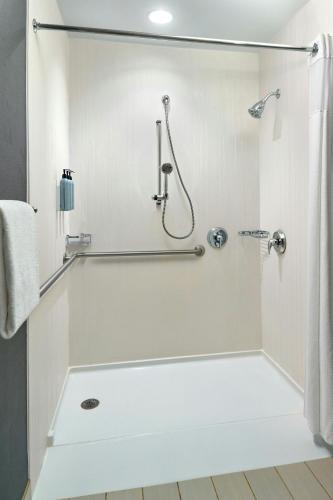 a white bathroom with a shower and a tub at Courtyard by Marriott Frederick in Frederick