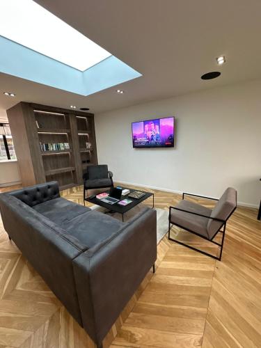 een woonkamer met een bank en een tv aan de muur bij Contemporary 3-Bed Penthouse with River Views in Londen