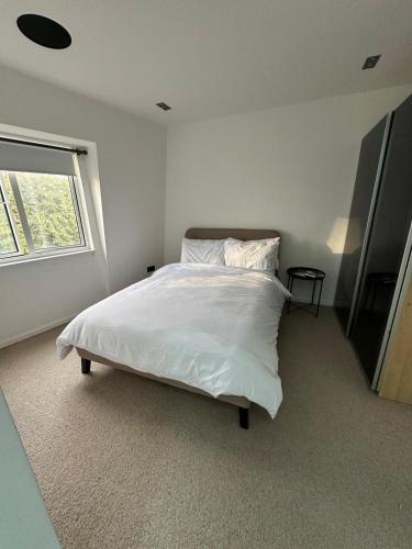 een slaapkamer met een bed met witte lakens en een raam bij Contemporary 3-Bed Penthouse with River Views in Londen