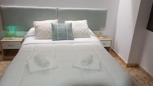 ein weißes Bett mit zwei Kissen und zwei Tischen in der Unterkunft Casa Cueva Roman in Setenil de las Bodegas