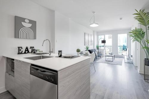 a white kitchen with a sink and a counter at Panoramic Skyline Penthouse Montreal Downtown -Free Parking - In Suite Laundry in Montréal