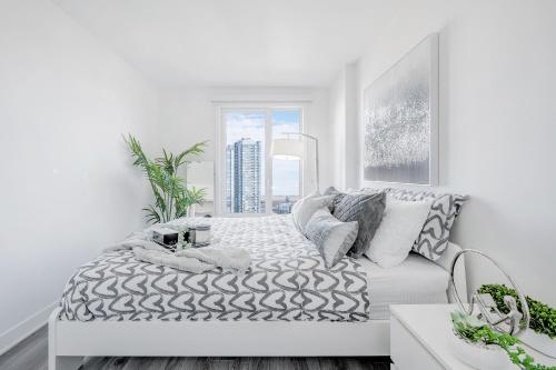 a white bedroom with a bed and a window at Panoramic Skyline Penthouse Montreal Downtown -Free Parking - In Suite Laundry in Montréal