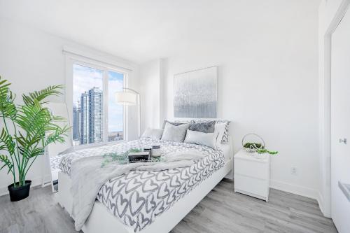 a white bedroom with a bed and a window at Panoramic Skyline Penthouse Montreal Downtown -Free Parking - In Suite Laundry in Montréal