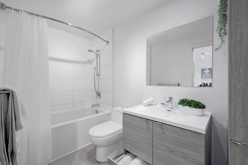 a white bathroom with a toilet and a sink at Panoramic Skyline Penthouse Montreal Downtown -Free Parking - In Suite Laundry in Montréal