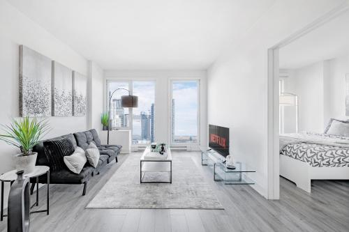 a white living room with a couch and a bed at Panoramic Skyline Penthouse Montreal Downtown -Free Parking - In Suite Laundry in Montréal