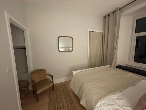 a bedroom with a bed and a chair and a mirror at Cosy Coastal getaway 2 bed flat in Largs in Largs