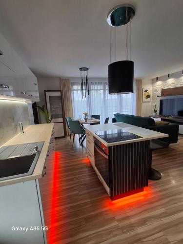 Eine Küche und ein Wohnzimmer mit einer Arbeitsplatte mit roten Lichtern in der Unterkunft Swiąteczny Apartament Rotembark in Rotembark
