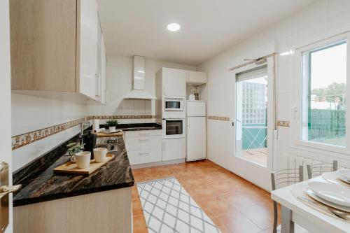 a kitchen with white cabinets and a large window at Casa Verde Logroño in Logroño