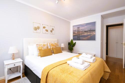 a white bedroom with a large bed with yellow sheets at Lisbon Relax Pool Apartment - Free Parking Garage in Lisbon