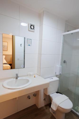a bathroom with a sink and a toilet and a mirror at Luísa Studio Hotel in Florianópolis