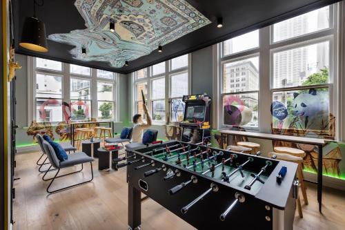 a room with a foosball table and chairs and windows at JO&JOE Auckland in Auckland