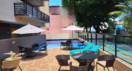 a patio with tables and chairs and a swimming pool at Flat Macaraípe - Maraca Beach I in Porto De Galinhas