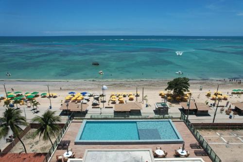 uma vista de uma praia com piscina, cadeiras e guarda-sóis em Nossa Praia Flats - Açores 109 Piscina Vista Panorâmica em Tamandaré