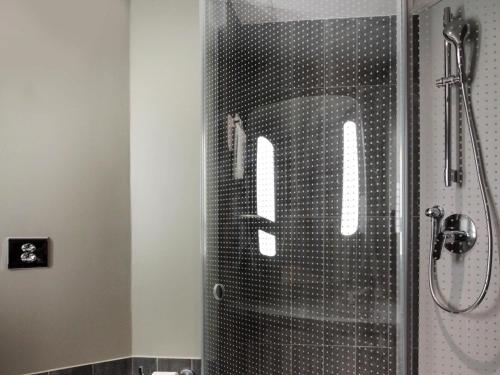 um chuveiro com uma porta de vidro com a letra m nela em ibis Cahors em Cahors