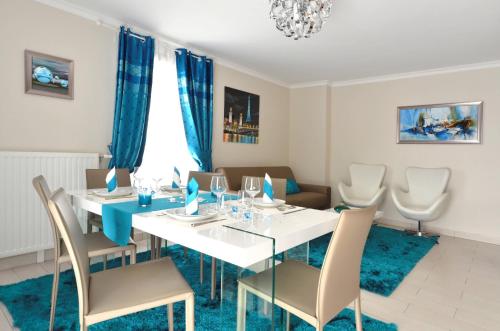 une salle à manger avec une table et des chaises blanches dans l'établissement Djanea Luxury Apartment - Disneyland Paris, à Serris