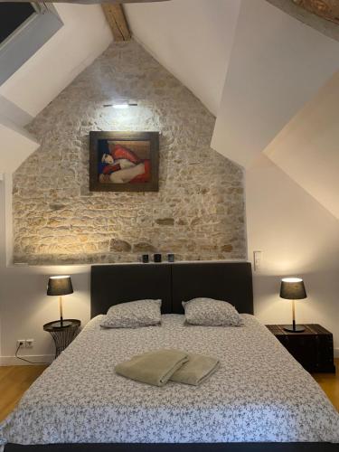 Un dormitorio con una cama y una pared de piedra. en Maison familiale climatisée, jardin cinema et jeux, en Épisy