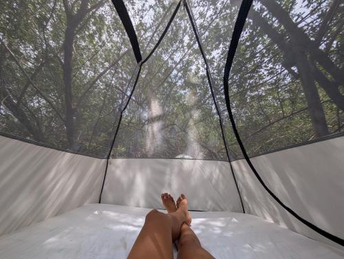 Commodity Camping Corazon Mazunte - Sol في مازونتي: شخص يستلقي على سرير في خيمة