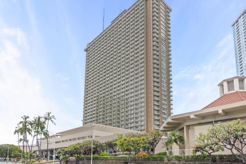 a tall building with palm trees in front of a building at Ala Moana Condo Hotel in Honolulu