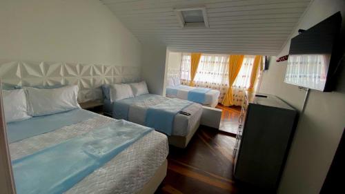 a hotel room with two beds and a television at Villa Santa Ines in Bogotá