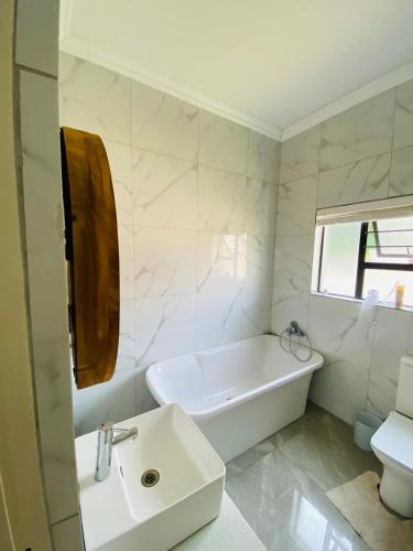 a white bathroom with a tub and a sink at ALIMU villa Mbombela in Nelspruit
