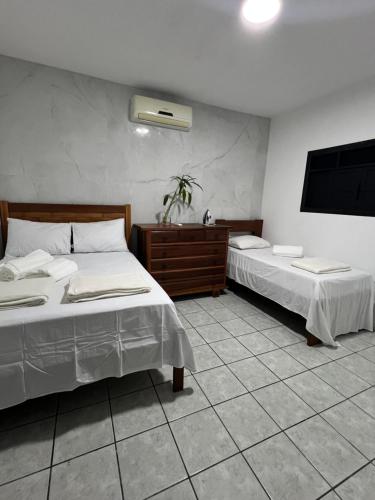 a bedroom with two beds and a television in it at Casa Limoeiro Tibau do Sul in Pipa