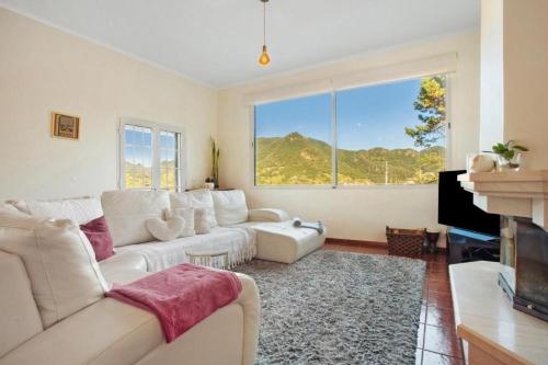 ein Wohnzimmer mit weißem Sofa und großem Fenster in der Unterkunft traveller's house in Machico
