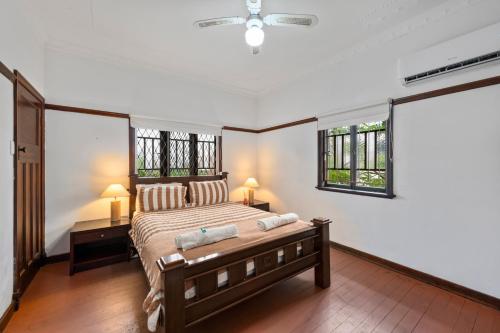 Comfortable 2 bedroom cottage في بريزبين: غرفة نوم بها سرير ونافذتين