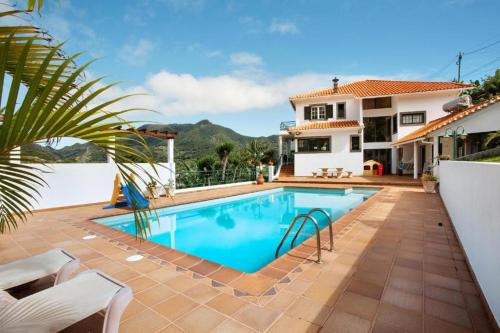 a swimming pool in front of a house at traveller's house PROMO 25 in Machico