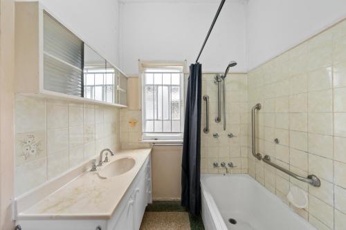 Comfortable 2 bedroom cottage في بريزبين: حمام مع حوض استحمام ومغسلة وحوض استحمام