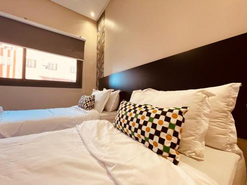 ein Schlafzimmer mit zwei Betten mit weißen Laken und Kissen in der Unterkunft Relax Family ApartHotel - Signature Residence in Ouarzazate