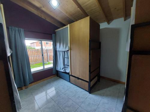 an empty room with a refrigerator and a window at Nomade bedbox Hostel in El Chalten