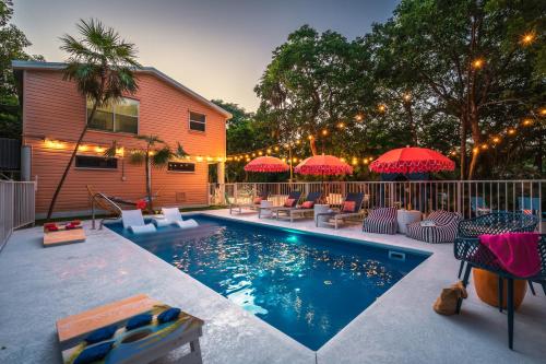 Una piscina con sillas y sombrillas al lado de una casa. en NEW!The HideawayPoolPickleballPutt-PuttKayaks!, en Marathon