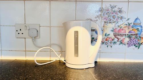 a white appliance sitting on a counter next to a outlet at Budget Shared Accommodation Luton 02 05 in Luton