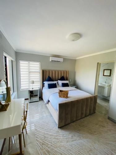 a bedroom with a large bed and a desk at ALIMU villa Mbombela in Nelspruit