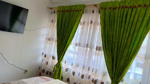 a bedroom with green curtains and a window at Villa Santa Ines in Bogotá