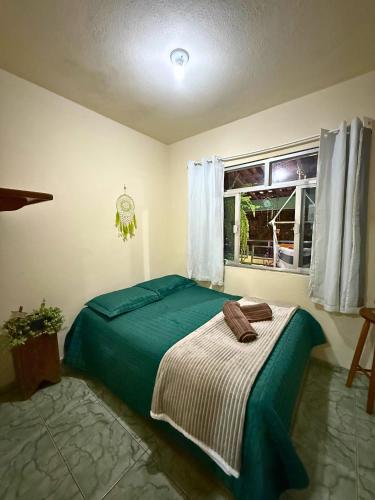 une chambre avec un lit vert et une fenêtre dans l'établissement Hostel Ninho das Harpias, à Divino de São Lourenço