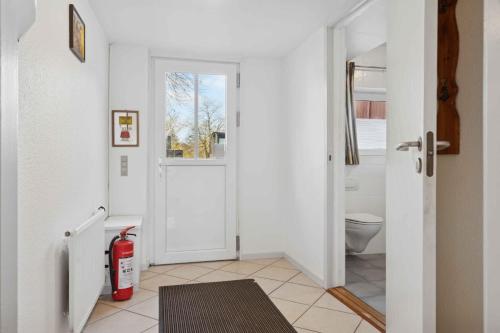 a bathroom with a white door and a toilet at Calm Holiday Home With Great Outings in Kollund
