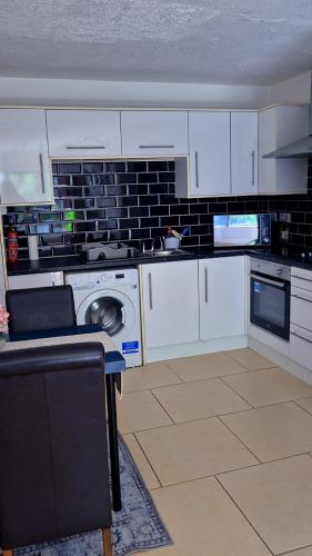 a kitchen with white cabinets and a washing machine at Entire 2bed apartment in Limerick