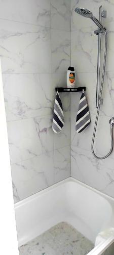 a white bathroom with a shower and a tub at Darwin Cottage in Kerikeri