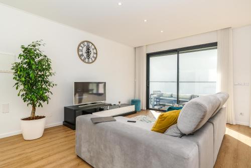 a living room with a couch and a clock on the wall at Villa Fenix II by Madeira Dream Stays in Câmara de Lobos